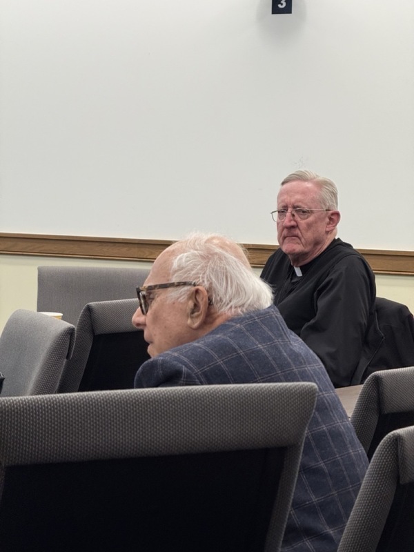 Two distinguished men listen to talk.