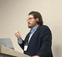 Man in navy suit speaks at conference