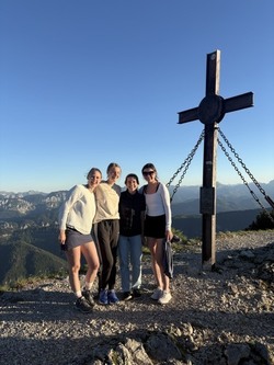 Students stand in front of cross and landscape.