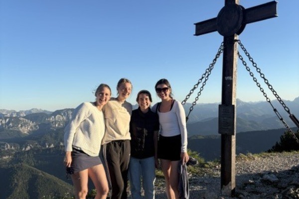Students stand in front of cross and landscape.